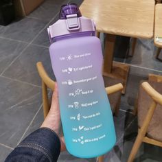 a person holding up a purple and blue water bottle with instructions on the side in front of a table