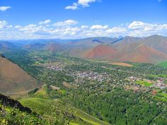 an aerial view of a town and mountains in the distance with blue skies above it