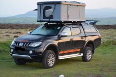 a truck with a camper attached to it's roof is parked in the grass