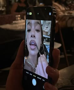 a person holding up a cell phone to take a selfie with her lips open