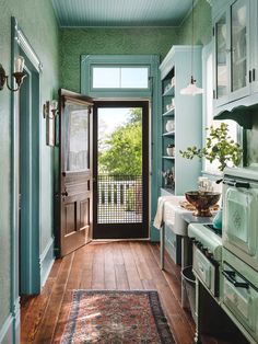 a kitchen with green walls and wood flooring next to an open door that leads to a balcony