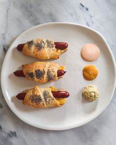 three hotdogs wrapped in bread on a plate with condiments and an egg