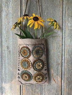 a bag hanging on the wall with flowers in it