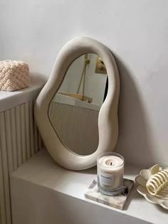 a white table topped with a mirror next to a candle