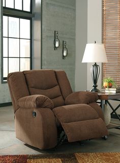 a living room with a brown recliner and lamp on the side table in front of it