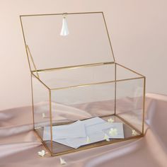 an open glass box with papers in it on a satin tablecloth covered flooring