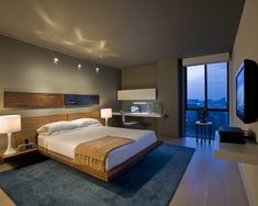 a bedroom with a large bed sitting next to a wall mounted tv on top of a wooden dresser