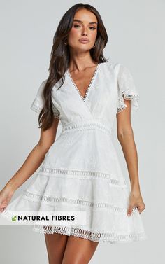 Get ready to turn heads in the Ariana Mini Dress! This stunning white A-line dress is perfect for any party or special occasion. The flutter sleeves and V-neck add a touch of femininity, while the A-line silhouette flatters every body shape. Made from comfortable cotton fabric, this dress can be worn all day and night without sacrificing style or comfort. Whether you're dancing the night away or enjoying a winter cocktail party, the Ariana Mini Dress is sure to make you feel confident and empowe White V-neck Dress For Garden Party In Spring, Elegant Flutter Sleeve Dress For Garden Party, Elegant A-line V-neck Dress With Ruffles, Feminine White Dress With Ruffle Hem, Party Dress With Flutter Sleeves And Lace Trim, Elegant Mini Dress With Flutter Sleeve For Garden Party, White A-line Dress For Brunch, Formal Summer Mini Dress With Flutter Sleeves, Flowy White Dress With Ruffle Sleeves