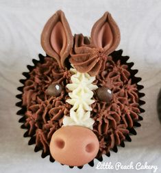 a cupcake shaped like a pig with chocolate frosting on it's face