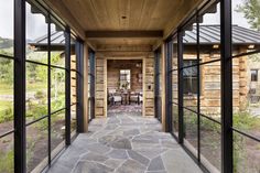 the inside of a house with glass walls and stone walkway leading to an outdoor dining area