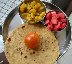 a metal plate topped with food next to a bowl of fruit