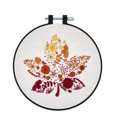 a white wall hanging with red and yellow flowers on it's side, in front of a white background