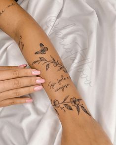 a woman's arm with flowers and butterflies on it, which is written in cursive writing