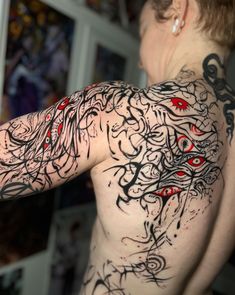 a woman with tattoos on her back has red eyes and black lines all over her body