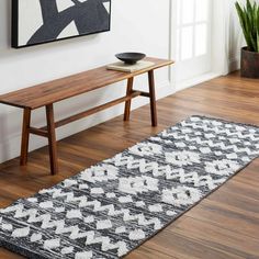 a wooden bench sitting next to a white rug on top of a hard wood floor