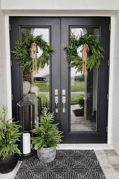 two wreaths are on the front door of a house with black and white rug