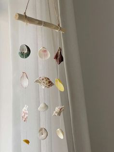 a mobile made out of seashells hanging from a curtain