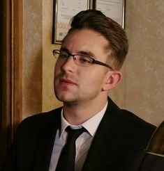 a man in a suit and tie looking off to the side with a serious look on his face