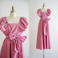 A very 80s bubblegum pink taffeta party dress, with ruffled elastic straps that can be pushed off-shoulder, if desired. It has a fitted bodice with a huge bowtie at the waist, and a very full, flowy skirt. ☛   m e a s u r e m e n t s   ☚ Best for: XS Bust: 33 Waist: 26 Hips: free Length, neckline to hem: 53 ☛   d e t a i l s   ☚ Era: 1980s Material: nylon, cotton Brand: Dance Allure Condition: excellent ☛   v i s i t   t h e   s h o p   ☚ https://etsy.me/2Nd23kg ☛ instagram ┇ poppycockvintage ☛ Pink Taffeta Dress For Summer, Pink Taffeta Party Dress, Summer Pink Taffeta Dress, Pink Taffeta Summer Dress, Elegant Pink Vintage Dress With Ruffles, Pink Taffeta Dress With Ruffles, Pink Retro Dresses With Ruffles, Vintage Pink Dress With Ruffles, 80’s Pink Prom Dress