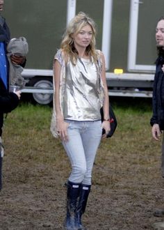 a woman standing in the mud wearing rain boots