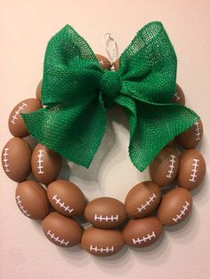 a wreath made out of wooden beads with a green bow on it and a football ornament