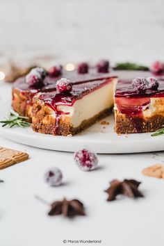 a cheesecake with cranberry sauce is on a plate next to crackers