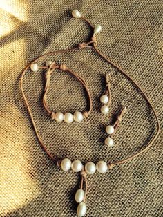 two necklaces with pearls are sitting on a cloth