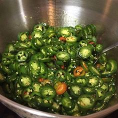 a large metal bowl filled with green peppers