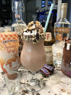 an ice cream sundae in a tall glass on a marble counter with liquor bottles behind it