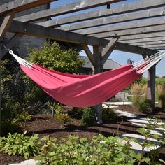 a pink hammock hanging from the side of a wooden pergolated structure