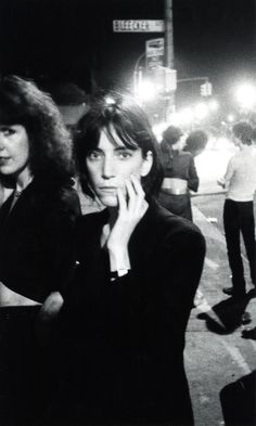 black and white photograph of two women standing on the side of a road at night