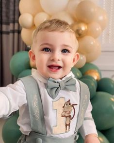 a little boy that is standing in front of some balloons and wearing a bow tie