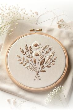 an embroidered floral arrangement on a white cloth with flowers in the center and two gold pins