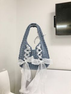 a crocheted purse hanging on the wall next to a toilet