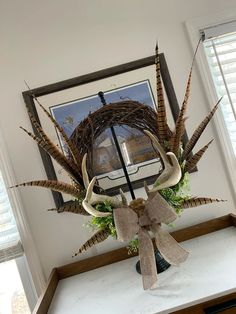 a wreath with deer antlers and greenery in front of a window