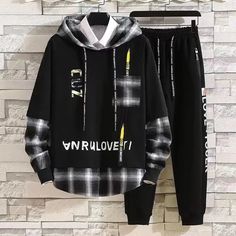 a black and white checkered hoodie and sweatpants are hanging on a brick wall