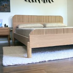 a bed sitting on top of a wooden floor next to a white rug