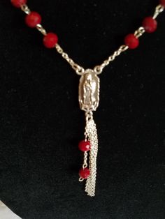 "This handmade Virgen De Guadalupe Necklace is made using Silver Tone curb chain that has triple layer and strung on 2 jump rings. Next are hand beaded individual links that connect to 12 connectors. At the bottom is a Silver Tone Medal of La Virgen De Guadalupe and on the reverse side has the wording \"Our Lady of Guadalupe\". Below that is a small jump ring with 4 2 1/2\" Chains with 2 chain and bead connector. All material used is new and non-vintage items. This necklace will arrive in a gift Adjustable Red Beaded Necklace With 8mm Beads, Adjustable Red Beaded Rosary, Spiritual Red Jewelry With Faceted Beads, Adjustable Red Beaded Necklace With Lobster Clasp, Adjustable Red Jewelry With Dangling Beads, Red Beaded Dangle Necklace, Red Beaded Dangle Necklaces, Guadalupe Necklace, Rosary Style Necklace