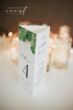 the table numbers are placed on top of each other in front of candles and greenery