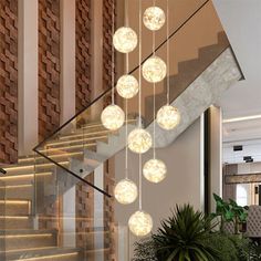 a bunch of lights hanging from the side of a stair case next to a potted plant