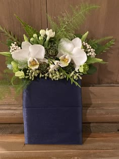 a blue vase filled with white flowers and greenery