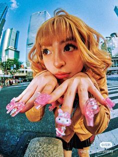 a girl with pink nails and hello kitty nail art on her hands in front of a cityscape