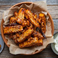 chicken wings with sesame seeds in a bowl on a wooden table next to other food items