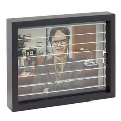 an office cubicle with a man wearing glasses and a tie on the window sill