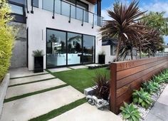 a modern home with grass and plants in front of the entrance to the house is shown