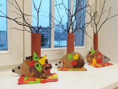 three vases filled with leaves and branches on top of a white counter next to a window