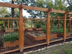 a fenced in vegetable garden with wooden posts and metal bars on the top level