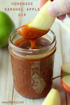 someone dipping an apple into a jar of homemade caramel apple dip