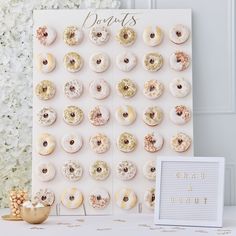 a white table topped with lots of donuts next to a sign that says doughnuts