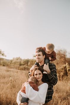 a man holding a baby while standing in a field